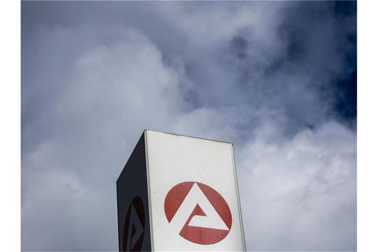 Wolken ziehen über ein Schild der Agentur für Arbeit und dem Berlin-Lichtenberg. Foto: Carsten Koall/dpa
