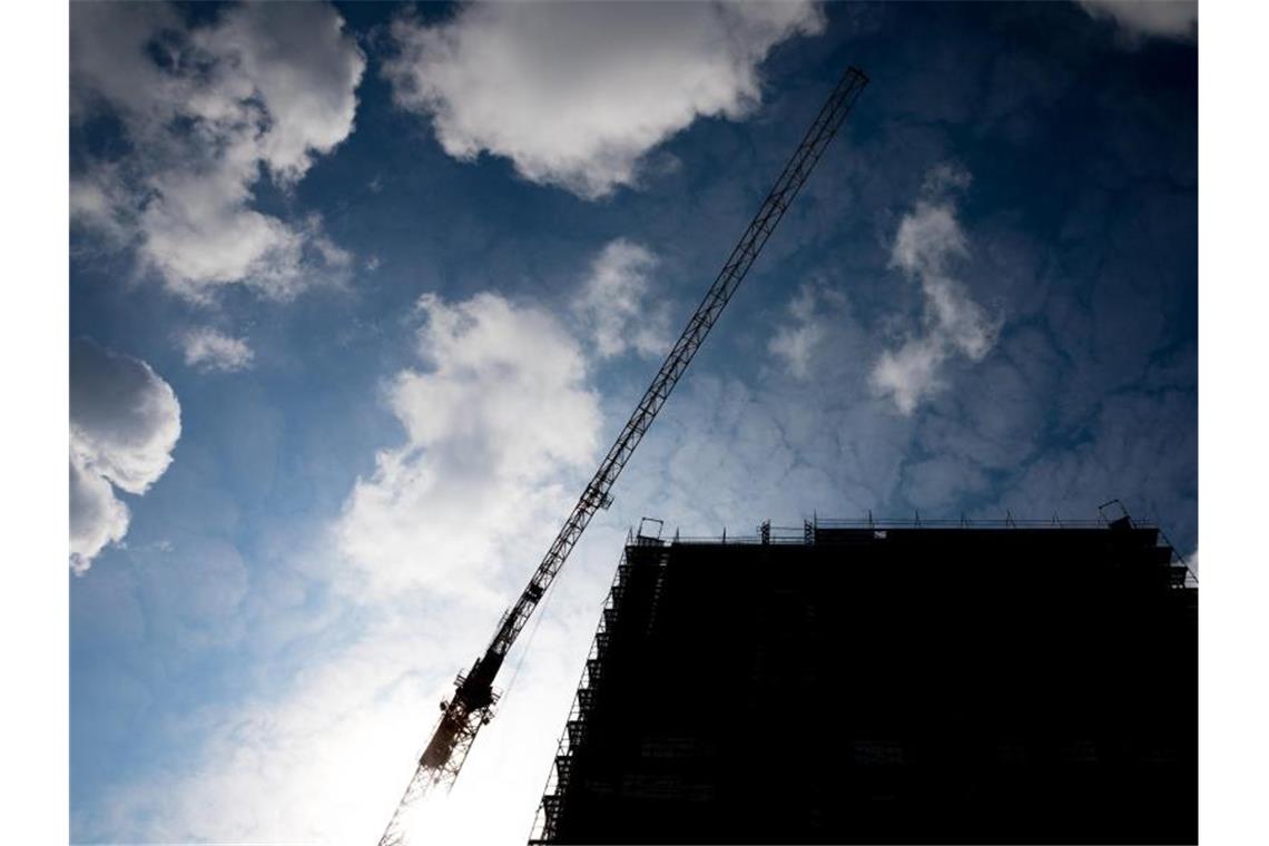 Bauwirtschaft weiterhin gut ausgelastet Wolken ziehen über einen Baukran und einem im Rohbau befindliches Gebäude hinweg. Foto: Moritz Frankenberg/Archiv