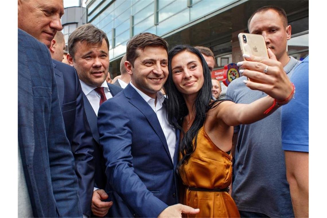 Präsident Selenskyj wird bei Ukraine-Wahl gestärkt Wolodymyr Selenskyj (3.v.l), Präsident der Ukraine, lässt sich mit einer Frau für ein Selfie fotografieren. Foto: Ukrinform/dpa