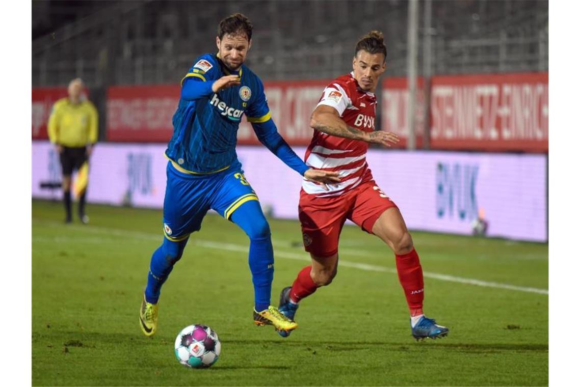 Würzburgs Rolf Feltscher (r) und Braunschweigs Nick Proschwitz teilten sich mit ihren Teams die Punkte. Foto: Nicolas Armer/dpa