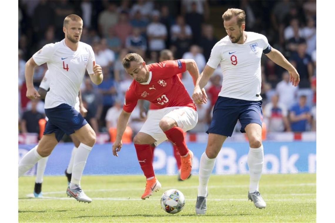 Xherdan Shaqiri (M) aus der Schweiz im Zweikampf mit Harry Kane. Foto: Jean-Christophe Bott/KEYSTONE