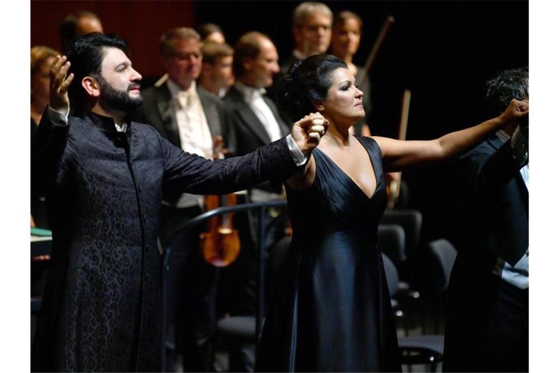 Netrebko und Eyvazov planen 2022 Konzert in Stuttgart Yusif Eyvazov, Anna Netrebko und Dirigent Mario Armiliato halten sich beim Applaus die Hände. Foto: Barbara Gindl/APA/dpa/Archivbild