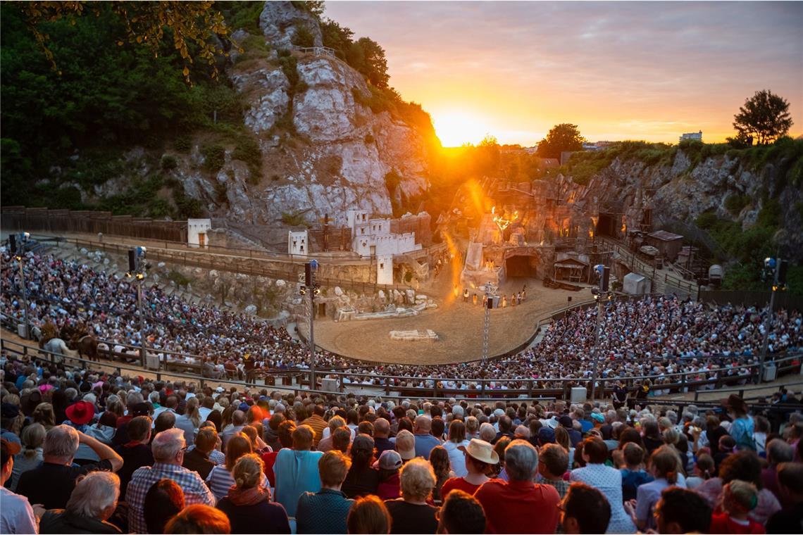 Karl May: Der Sachse, der Old Shatterhand war Zahlreiche Besucher verfolgen eine Aufführung der Karl-May-Spiele in Bad Segeberg vor dem Kalkberg neben der untergehenden Sonne. Seit 1952 werden im Kalkbergstadion von Bad Segeberg Karl Mays Abenteuerromane auf die Bühne gebracht.
