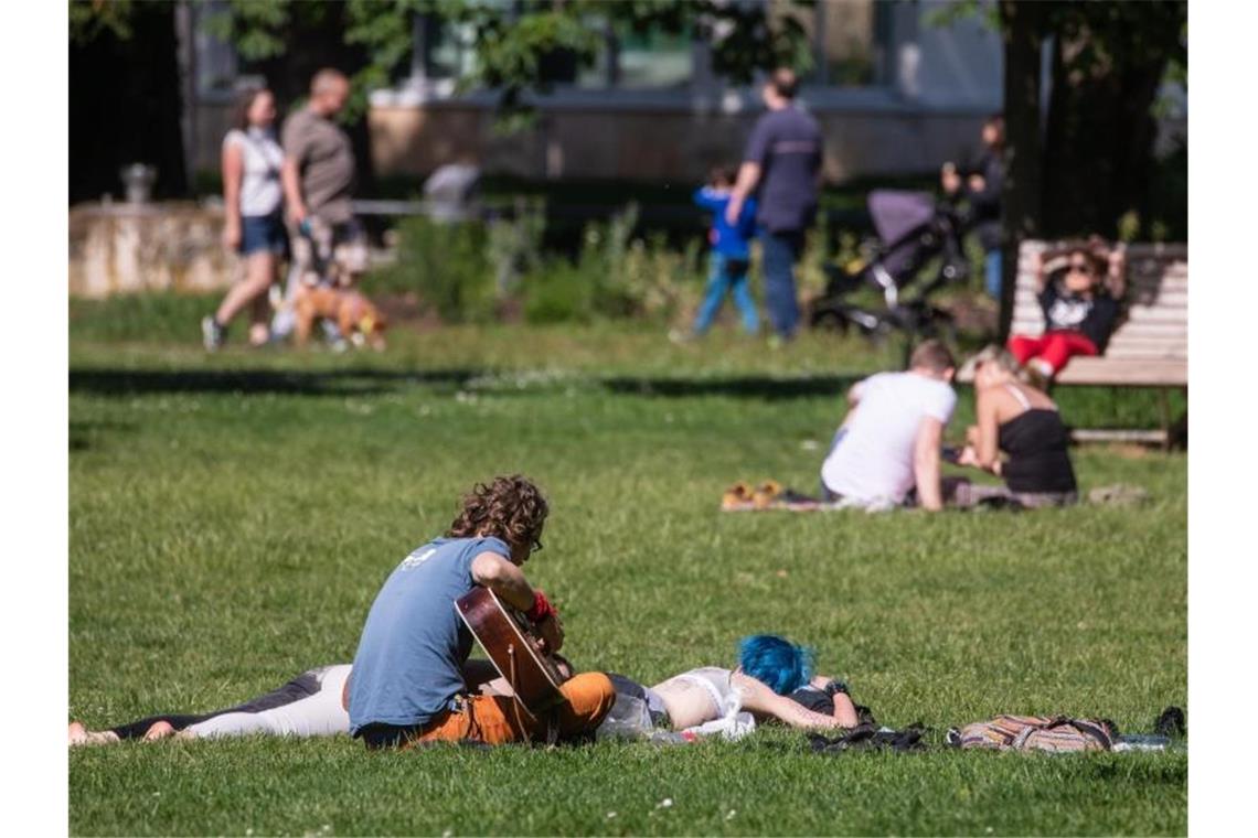 Zahlreiche Menschen genießen im Kurpark die Sonne. Foto: Christoph Schmidt/dpa/Archivbild