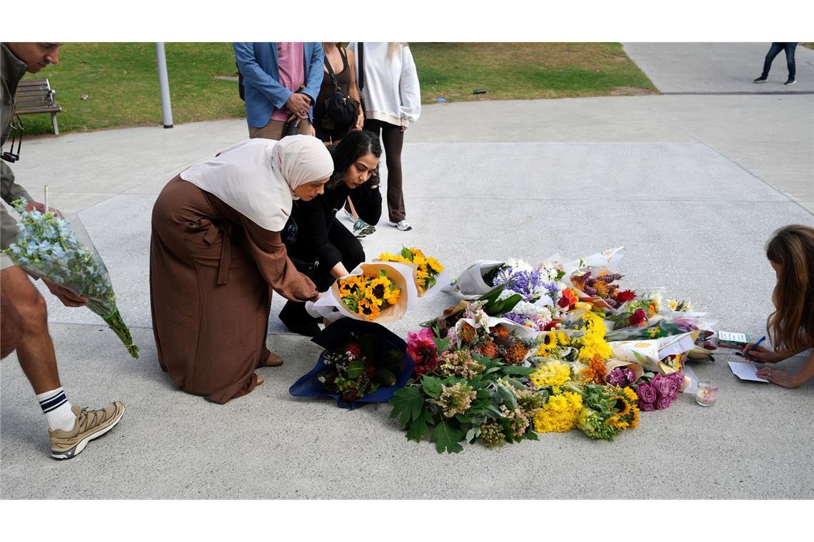 Zahlreiche Menschen legen am Tatort Blumen nieder.