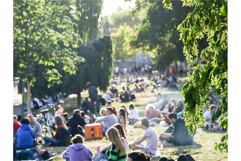 Zahlreiche Menschen sitzen im Licht der untergehenden Sonne auf einer Wiese im James-Simon-Park. Abends und nachts soll der Besuch künftig nicht mehr erlaubt sein. Foto: Jens Kalaene/dpa-Zentralbild/dpa