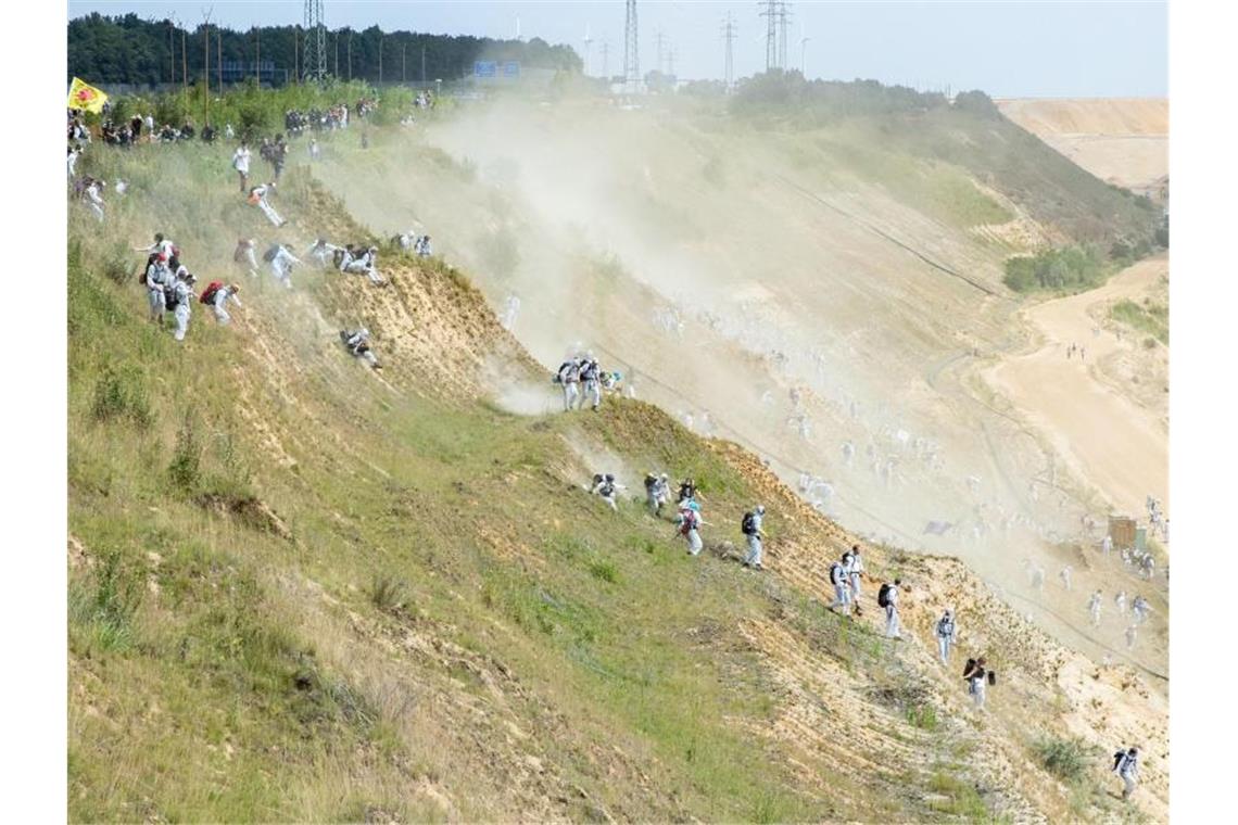 Zahlreiche Umweltaktivisten laufen in den Tagebau Garzweiler, nachdem sie die Polizeisperre durchbrochen haben. Foto: Marcel Kusch