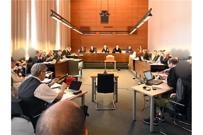 Zu Beginn des Prozesses sitzen elf Angeklagte und Justizbeamte im Landgericht seitlich hinter ihren Anwälten. Foto: Patrick Seeger/dpa