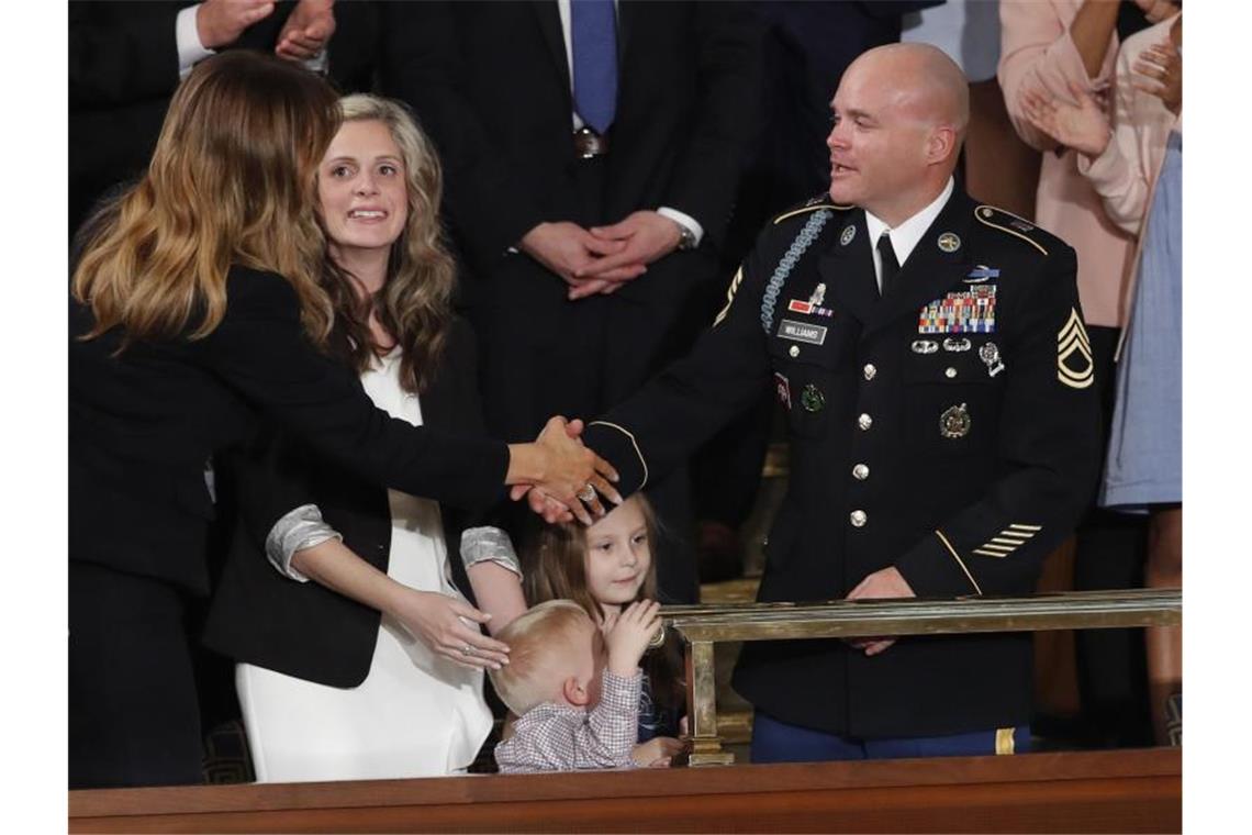 Zu Gast im Kongress war auch Soldaten-Gattin Amy Williams (2.v.l.) mit ihren Kindern. Trump überraschte sie mit der Nachricht, dass ihr Mann, Feldwebel Townsend Williams (r), vom Einsatz zurück sei, woraufhin die Familie vor laufenden Kameras wiedervereint wurde. Foto: J. Scott Applewhite/AP/dpa