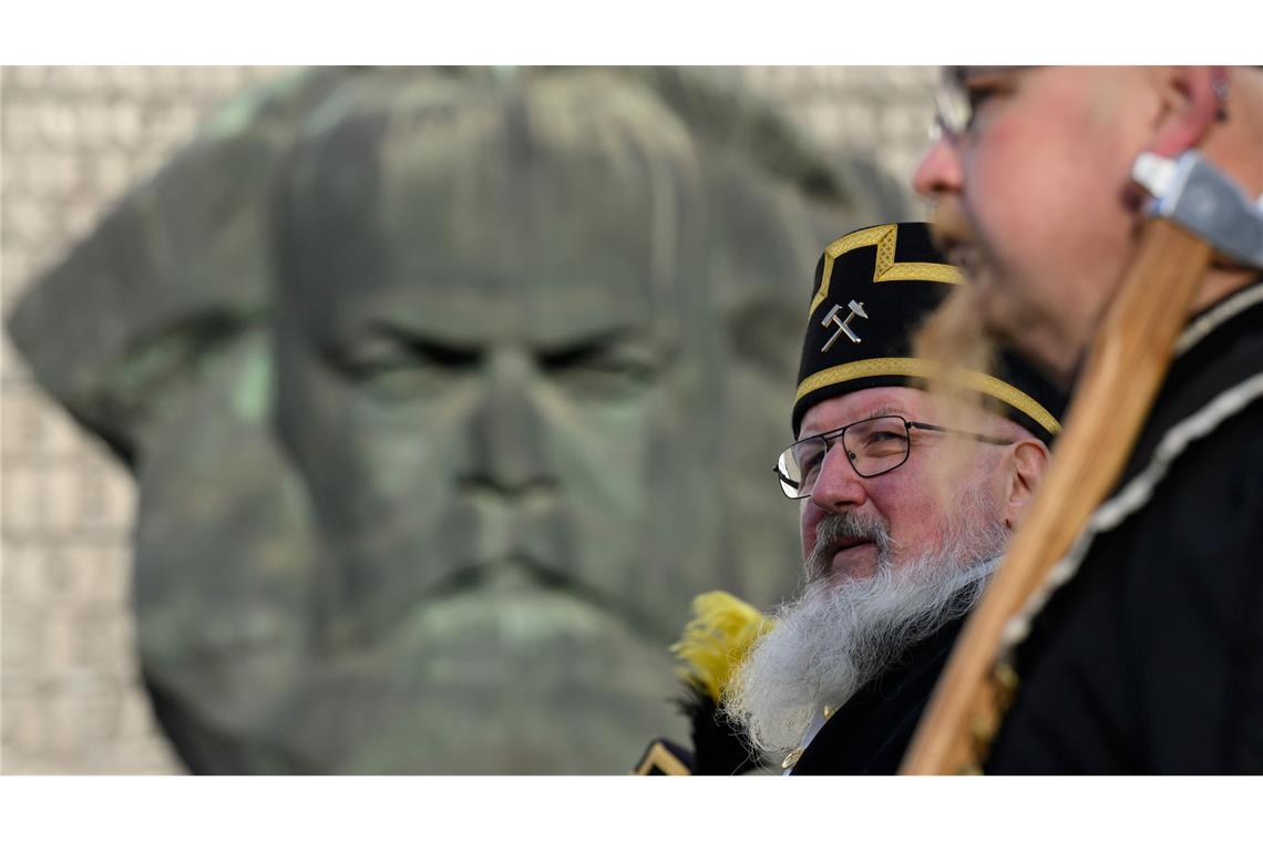 Zum Abschluss des Kulturhauptstadtjahres in Chemnitz ziehen Teilnehmer der Bergparade im traditionellen Habit am Karl-Marx-Monument vorbei.