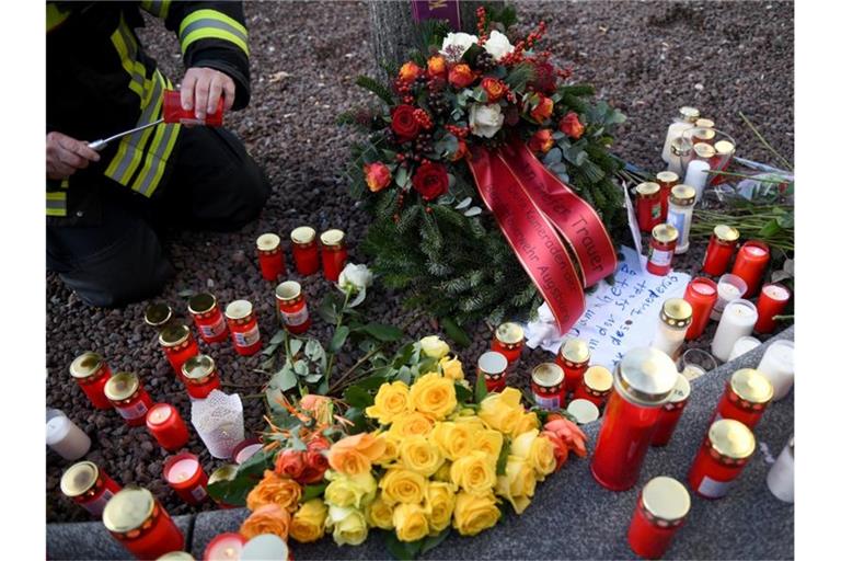 Zur Erinnerung an das Opfer zündet ein Feuerwehrmann am Königsplatz in Augsburg eine Kerze an. Foto: Stefan Puchner/dpa/Archiv