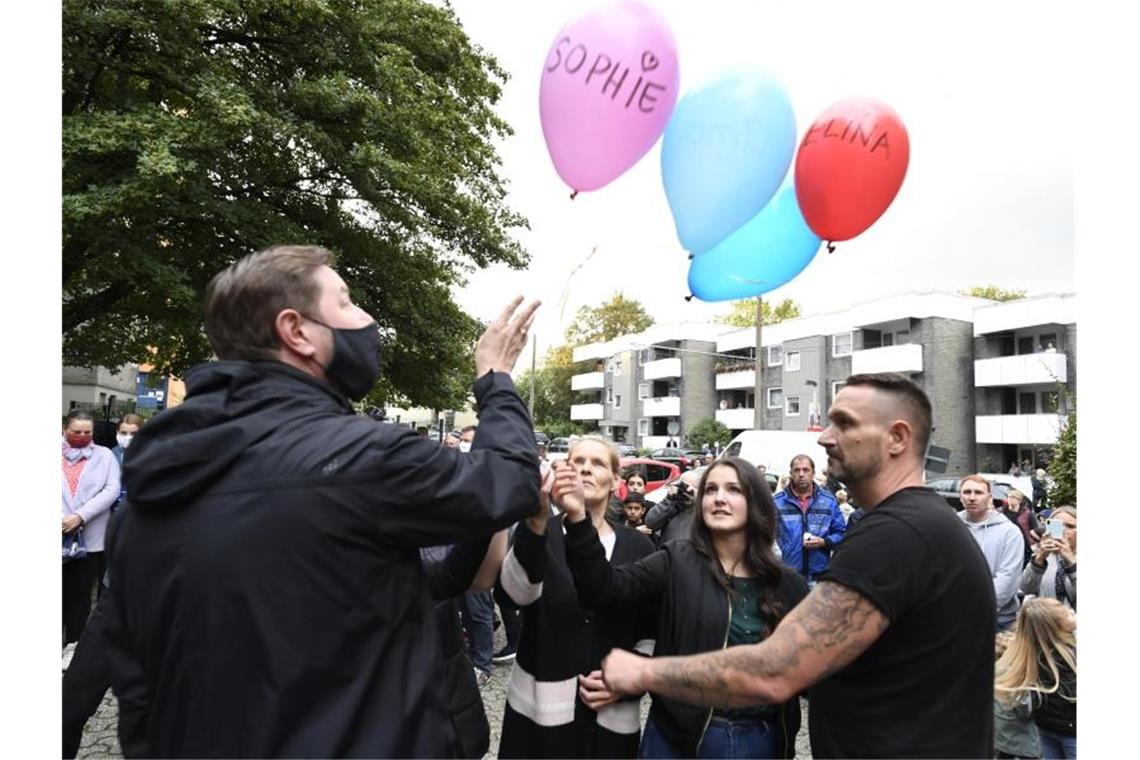 Zusammen mit Oberbürgermeister Tim Kurzbach (l) lassen Nachbarn als Ausdruck ihrer Trauer fünf Luftballons mit den Namen der fünf getöteten Kinder vor dem Haus der Familie steigen. Foto: Roberto Pfeil/dpa