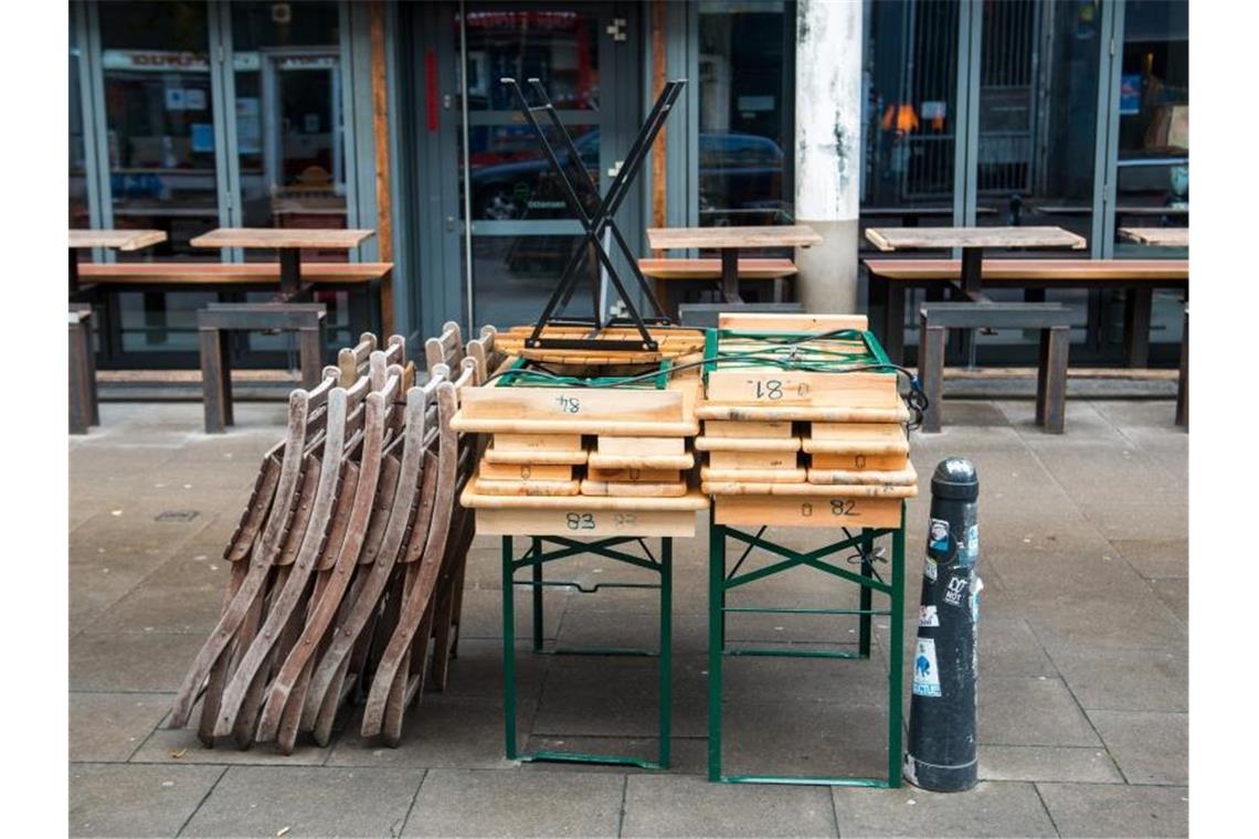 Wenig Hoffnung auf schnelle Corona-Lockerungen Zusammengestellte Tische und aufgestapelte Stühle stehen vor einem geschlossenen Café in Hamburg. Foto: Daniel Bockwoldt/dpa
