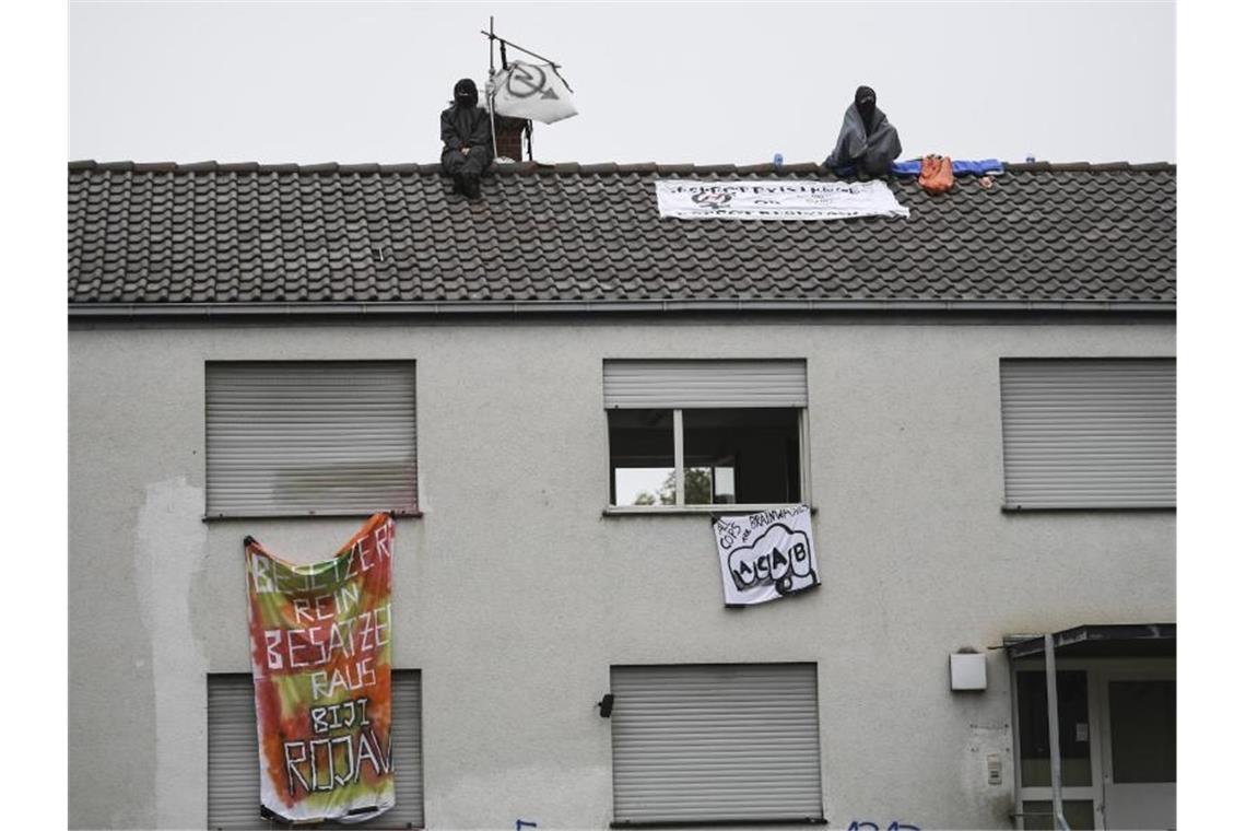 Zwei Aktivisten sitzen auf dem Dach eines ehemaligen Polizeipostens. Foto: Patrick Seeger/dpa/Archivbild