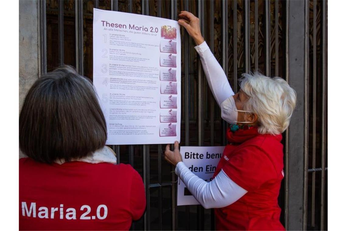 Thesenanschlag: Reformbewegung Maria 2.0 protestiert Zwei Aktivistinnen der katholischen Reforminitiative Maria 2.0 hängen ein Plakat mit ihren Thesen an das Hauptportal des Münsters. Foto: Philipp von Ditfurth/dpa