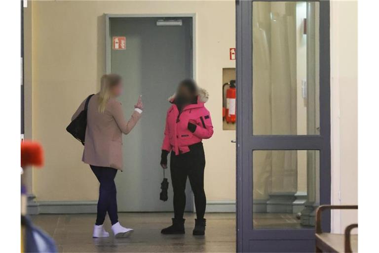 Zwei angeklagte Frauen warten vor einem Gerichtssaal im Strafjustitzgebäude in Hamburg auf den Beginn der Verhandlung. Foto: Ulrich Perrey/dpa