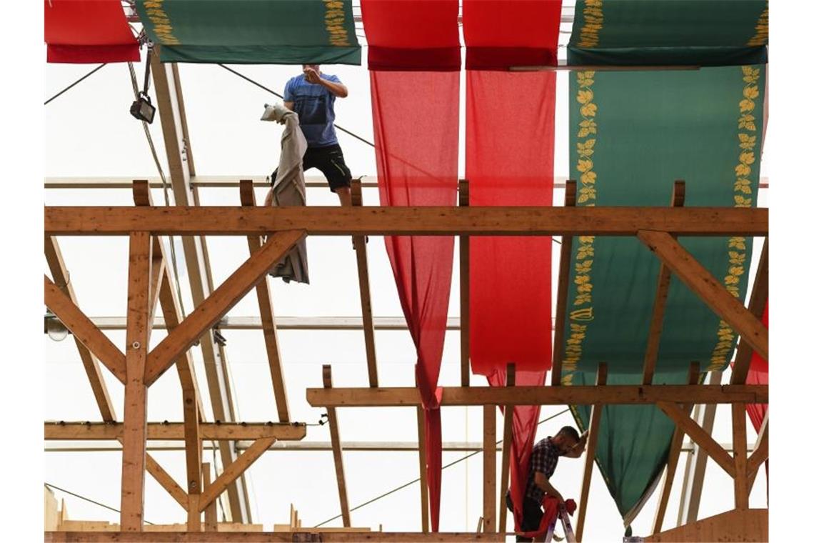 Countdown zum Cannstatter Volksfest: Aufbau in heißer Phase Zwei Arbeiter befestigen in einem Bierzelt Stoffbänder an der Decke. Foto: Edith Geuppert