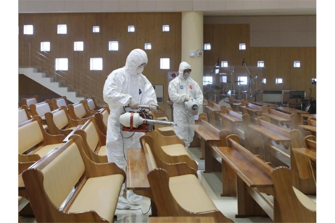 Zwei Arbeiter in Schutzkleidung versprühen Desinfektionsmittel in einer Kirche in Südkorea. Foto: -/YNA/dpa