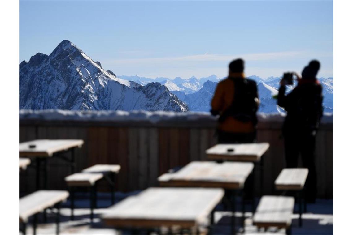 Skigebiete trotz Corona zuversichtlich Zwei Besucher fotografieren von der Zugspitze aus das Panorama des Wettersteingebirges. Nach gut eineinhalbjähriger Pause wegen Corona sollen dort wieder Lifte laufen und Skifahrer ihre Schwünge ziehen. Foto: Angelika Warmuth/dpa