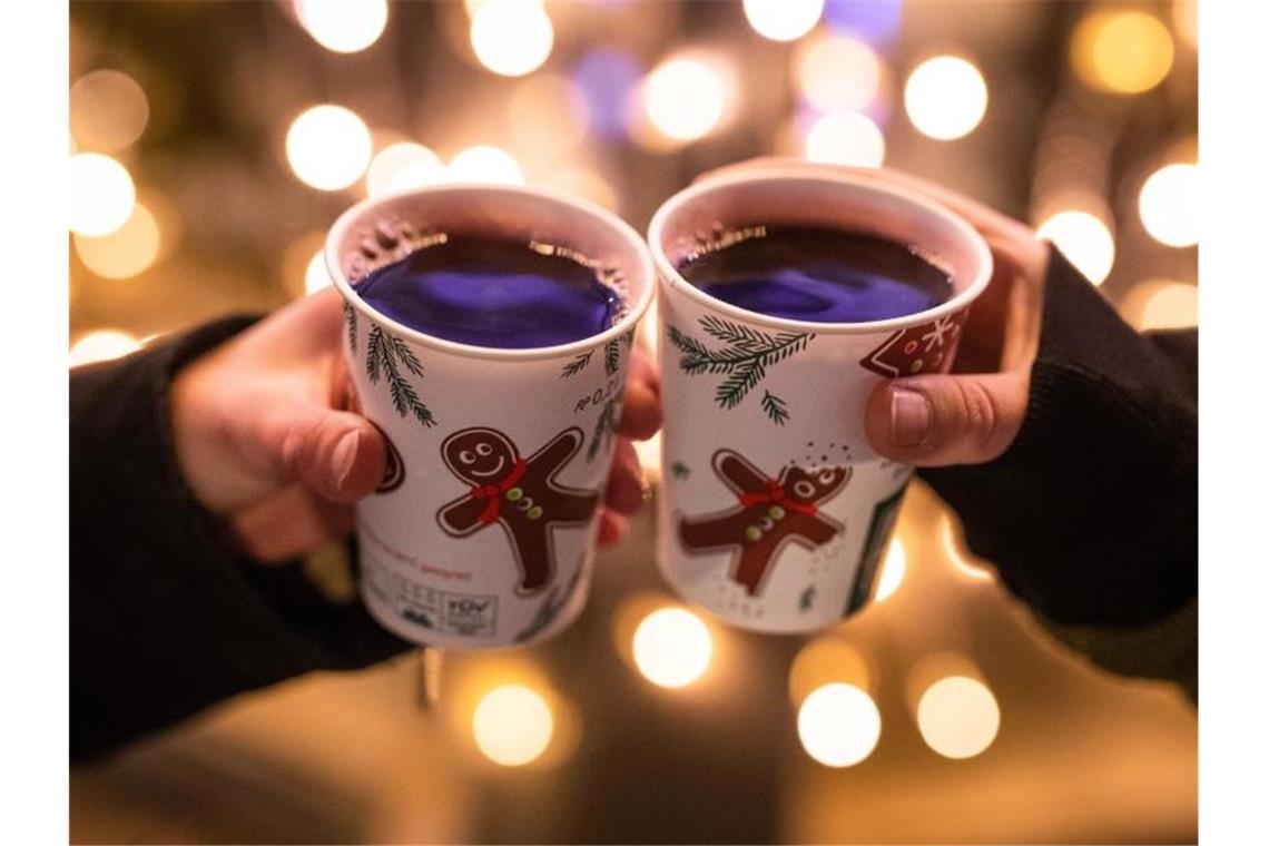 Corona-Lage: Weitere Weihnachtsmärkte abgesagt Zwei Besucherinnen eines Weihnachtsmarktes stoßen mit Glühwein an. Foto: Christoph Schmidt/dpa/Symbolbild