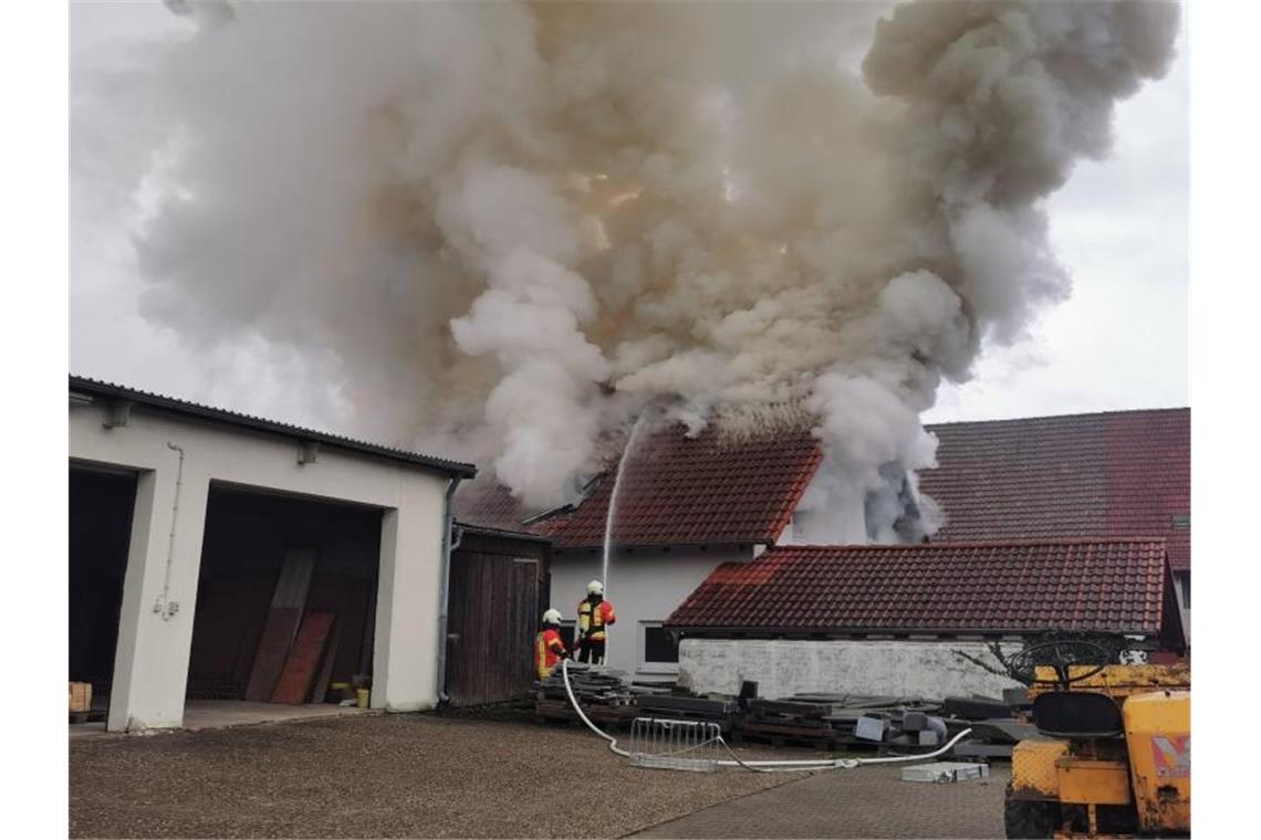 Zwei Einsatzkräfte der Feuerwehr versuchen eine meterhohe Rauchsäule in einem Wohnhaus im Landkreis Heilbronn zu löschen. Foto: Julian Buchner/Einsatz-Report24/dpa