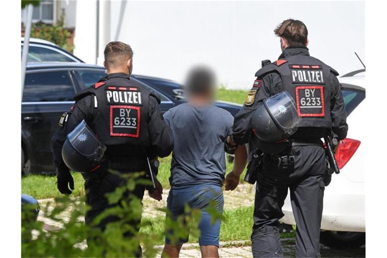 Zwei Einsatzkräfte der Polizei führen in Miesbach einen Tatverdächtigen ab. Foto: Tobias Hase/dpa