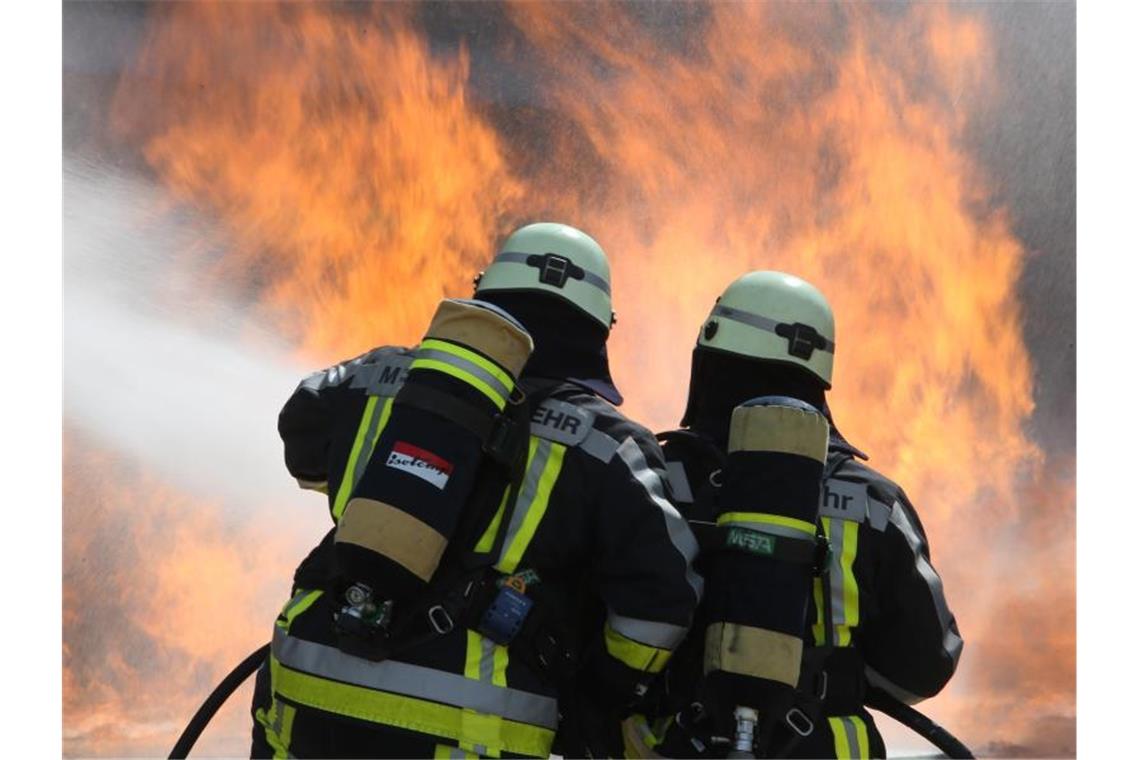 Zwei Feuerwehrmänner führen Löscharbeiten an einer Simulationsanlage durch. Foto: Stephan Jansen/dpa