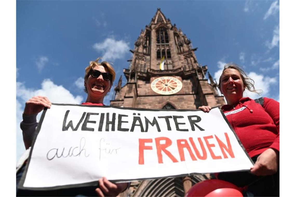 Zwei Frauen der Initiative Maria 2.0 werben vor dem Freiburger Münster für „Weiheämter auch für Frauen“. Foto: Patrick Seeger