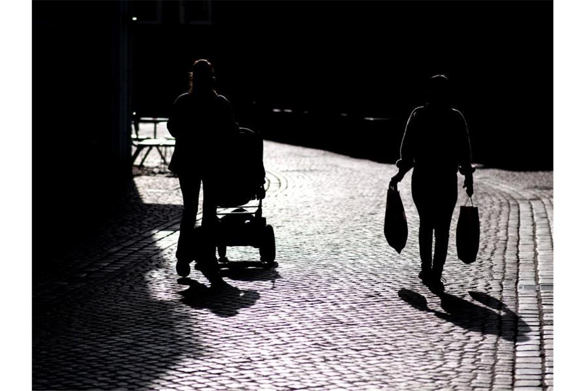 Zwei Frauen gehen im Gegenlicht durch eine Straße in der Innenstadt von Oldenburg. Foto: Hauke-Christian Dittrich/dpa