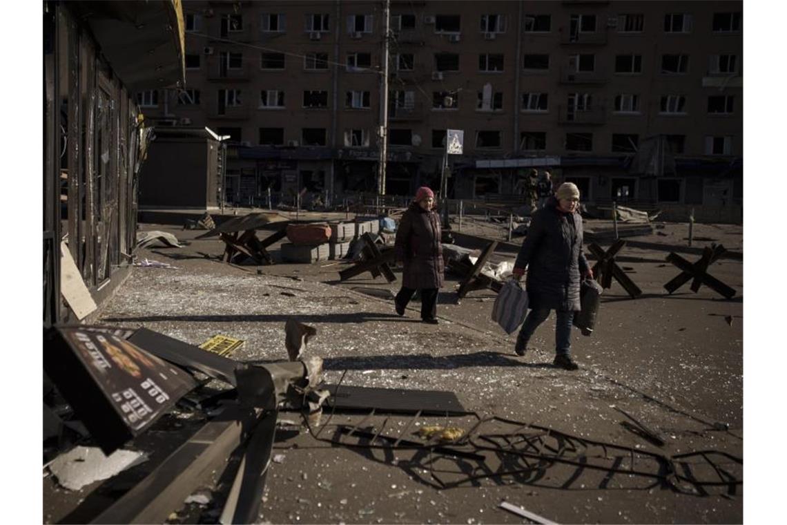 Krieg gegen die Ukraine: So ist die Lage Zwei Frauen gehen nach einem Bombenangriff in Kiew eine Straße entlang, auf der Trümmer von beschädigten Gebäuden sowie Panzerabwehr-Igel liegen. Foto: Felipe Dana/AP/dpa
