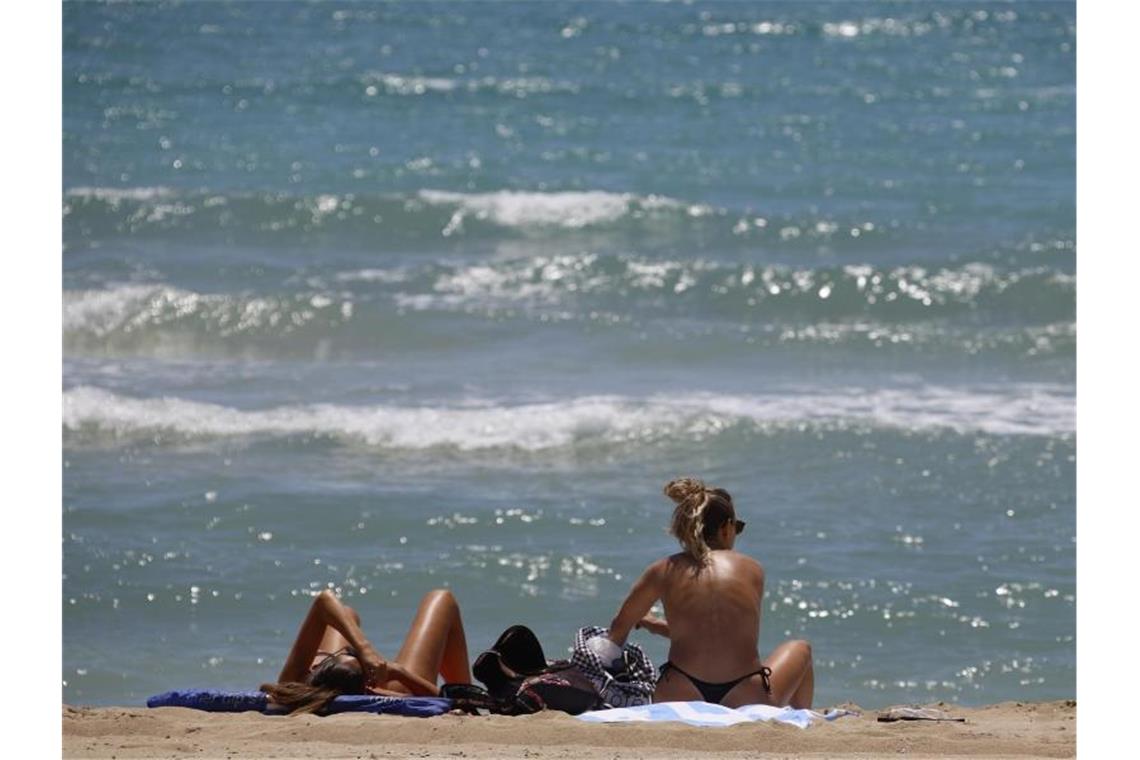 Zwei Frauen sonnen sich am Playa de Palma. Die ersten deutschen Touristen sind am Montagmorgen auf Mallorca gelandet. Foto: Clara Margais/dpa