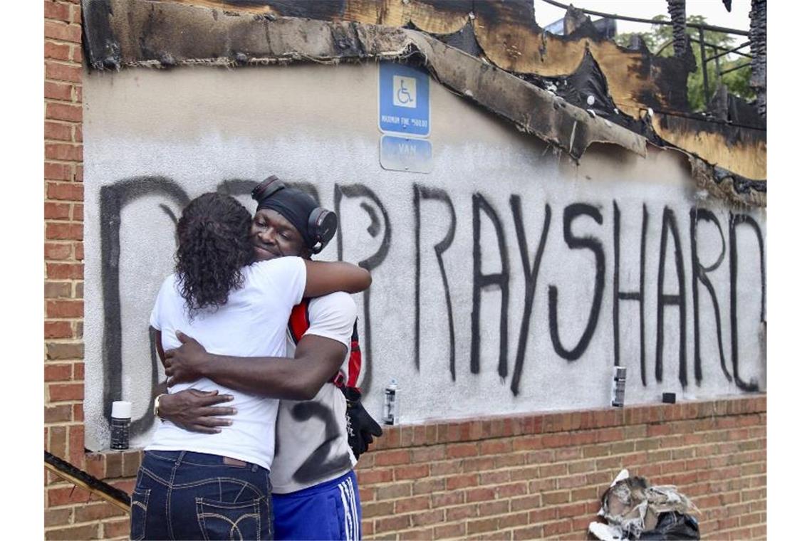 Empörung über Polizei in Atlanta Zwei Frauen umarmen sich vor dem Schriftzug „Ruhe in Frieden Rayshard“, den eine der beiden Frauen aufgesprüht hatte. Foto: Steve Schaefer/Atlanta Journal-Constitution/AP/dpa