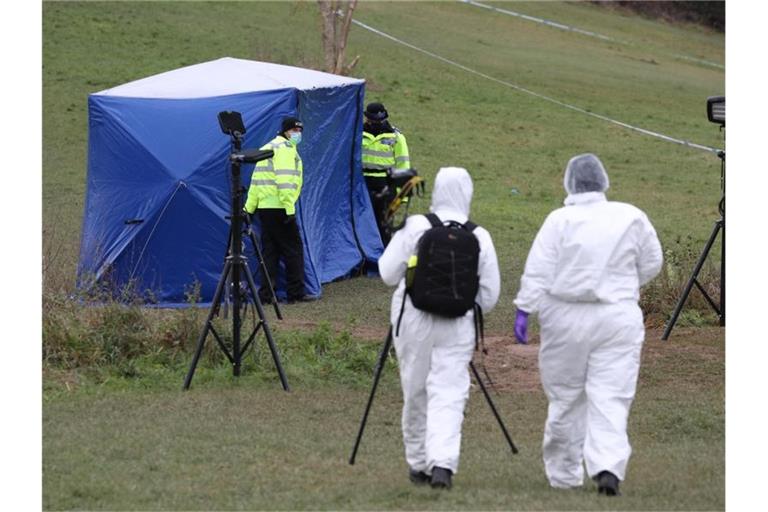 Zwei Gerichtsmediziner gehen zu einem Zelt am Tatort auf dem Bugs Bottom Feld. Fünf Jugendliche sollen hier im Januar einen 13-jährigen Jungen erstochen haben. Foto: Jonathan Brady/PA Wire/dpa