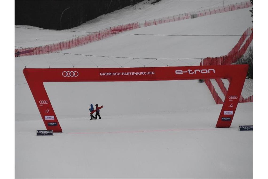 Deutsche Ski-Asse vor komplizierten WM-Tests Zwei Helfer gehen in Garmisch hinter dem Zielbogen vorbei. Das zweite Training wurde wegen zu schlechtem Wetters abgesagt. Foto: Angelika Warmuth/dpa