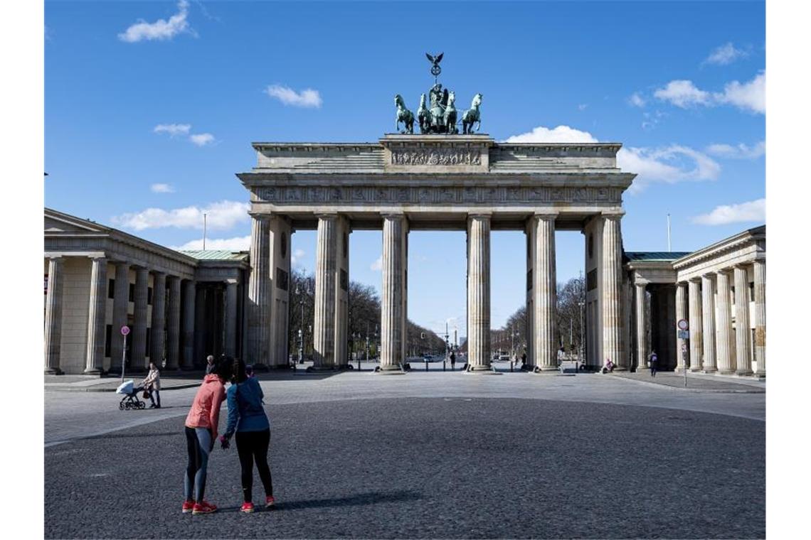 Zwei Joggerinnen machen auf dem sonst gut besuchten Pariser Platz vor dem Brandenburger Tor in Berlin ein Selfie. Foto: Fabian Sommer/dpa