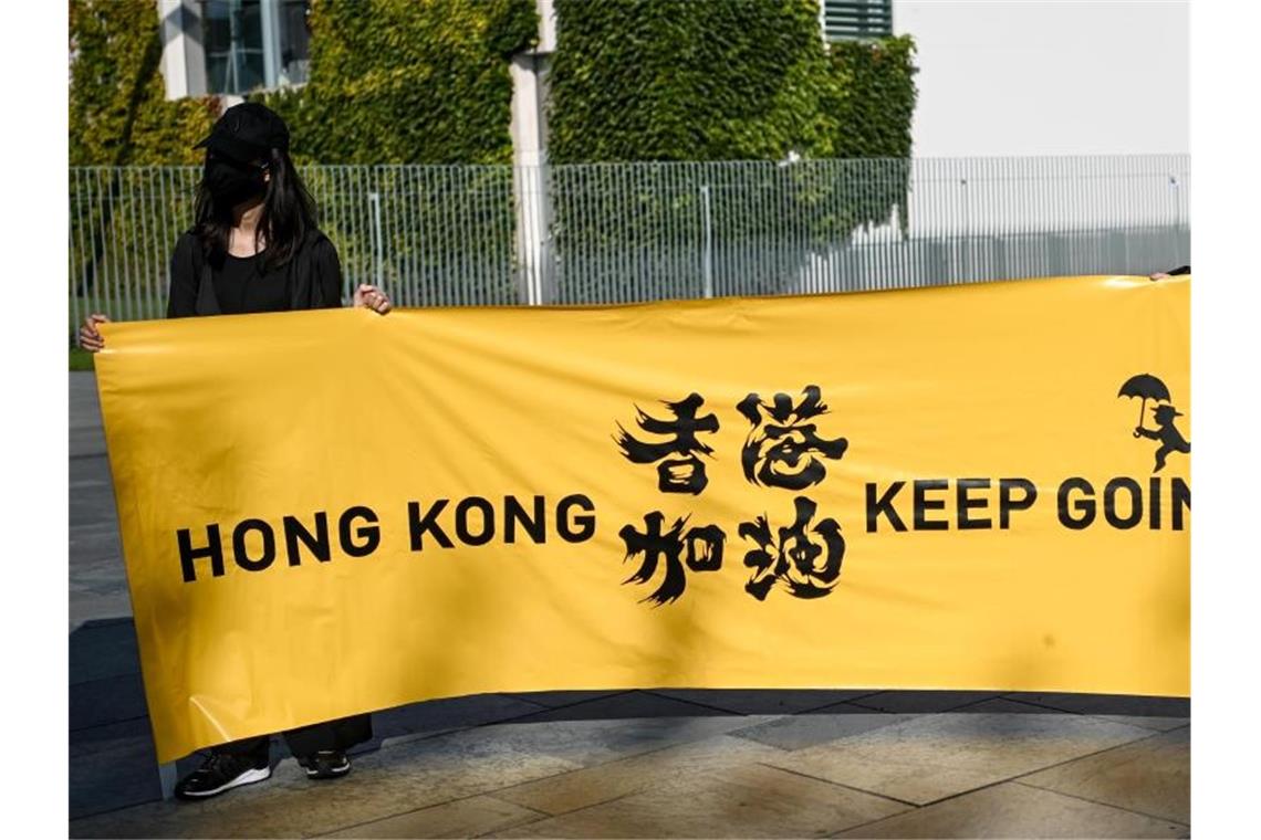 Zwei junge Frauen halten ein Transparent mit der Aufschrift „Hong Kong keep going“ bei einer Menschenrechtsaktion vor dem Bundeskanzleramt. Menschenrechtsverletzungen in Ländern wie China, können von der Europäischen Union künftig deutlich einfacher sanktioniert werden. Foto: Britta Pedersen/dpa-Zentralbild/dpa