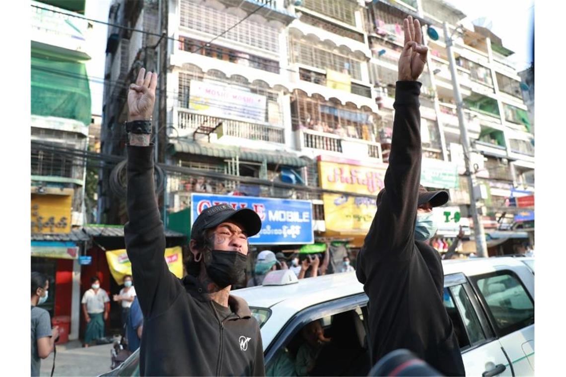 Zwei Männer erheben die Hände zu einem Drei-Finger-Gruß, als Zeichen des Widerstandes, aus Protest gegen den Militärputsch. Foto: Str/AP/dpa