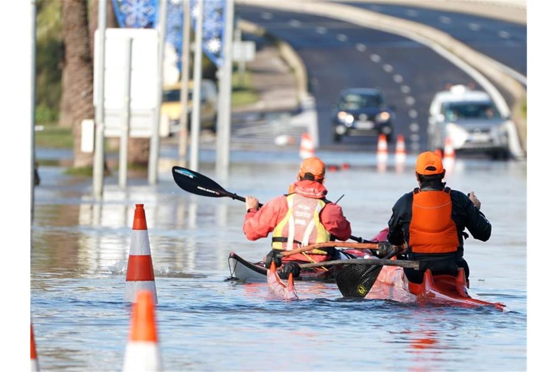 Zwei Männer paddeln mit ihren Kajaks durch die überflutete Straße in Palavas-les-Flots nach einem nächtlichen Sturm in Südfrankreich. Foto: PASCAL GUYOT/AFP/dpa