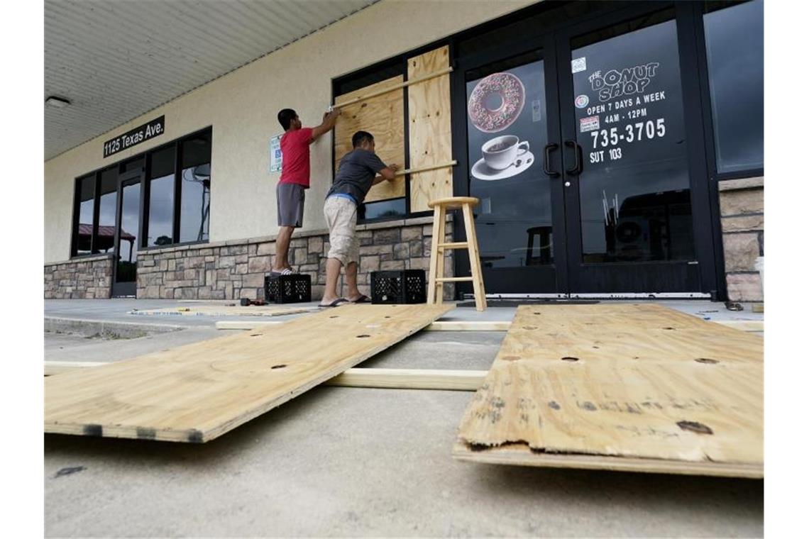 Hurrikan „Laura“ fegt über Teile der USA Zwei Männer sichern ihr Geschäft mit Holzplatten. Foto: Eric Gay/AP/dpa