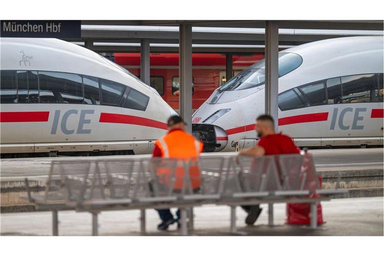 Zwei Männer sitzen am Morgen, nach dem bundesweiten Ausfall bei der Deutschen Bahn, am Hauptbahnhof München vor einem ICE-Zug. Die Störung bei der Deutschen Bahn ist nach Unternehmensangaben behoben. Der Zugverkehr läuft wieder an, es wird aber zu Folgeverspätungen und kurzfristigen Fahrtausfällen kommen.