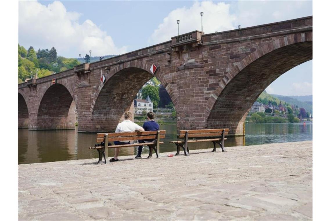 Wetterbilanz: Kühler, aber sonniger Frühling im Südwesten Zwei Männer sitzen vor der Alten Brücke auf einer Bank am Neckar. Foto: Uwe Anspach/dpa/archivbild