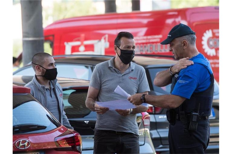 Zwei Männer sprechen am Grenzübergang mit einem Grenzbeamten und zeigen Dokumente vor. Foto: Alessandro Crinari/KEYSTONE/Ti-Press/dpa