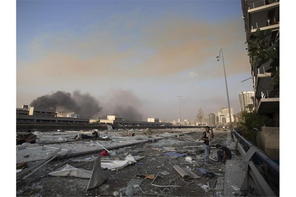 Zwei Männer stehen inmitten von Trümmern. Foto: Hassan Ammar/AP/dpa
