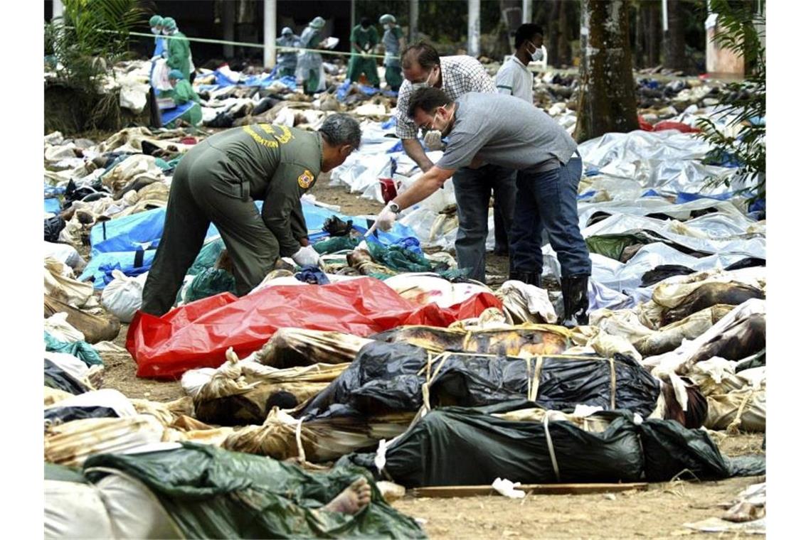 Gebete für Opfer am 15. Jahrestag der Tsunami-Katastrophe Zwei Männer suchen unter den Opfern von Khao Lak nach Verwandten. Foto: epa Rungroj Yongrit/epa/dpa