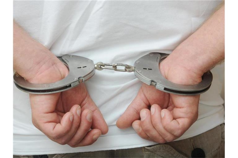 Zwei männliche Hände sind in Polizeihandschellen gefesselt. Foto: Uli Deck/Archiv