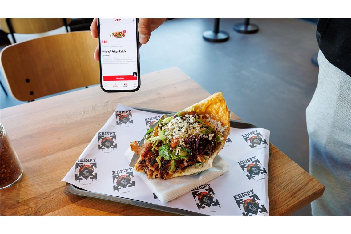 Zwei Mal Krispy Kebab: einmal auf dem Smartphone in der KFC-App und einmal auf einem Tablett in einer Krispy-Kebab-Filiale.