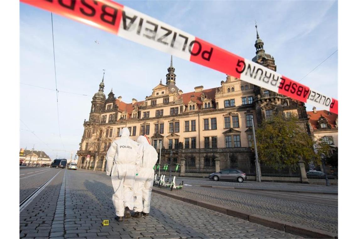 Zwei Mitarbeiter der Spurensicherung stehen vor dem Residenzschloss mit dem Grünen Gewölbe hinter einem Absperrband. Foto: Sebastian Kahnert/zb/dpa