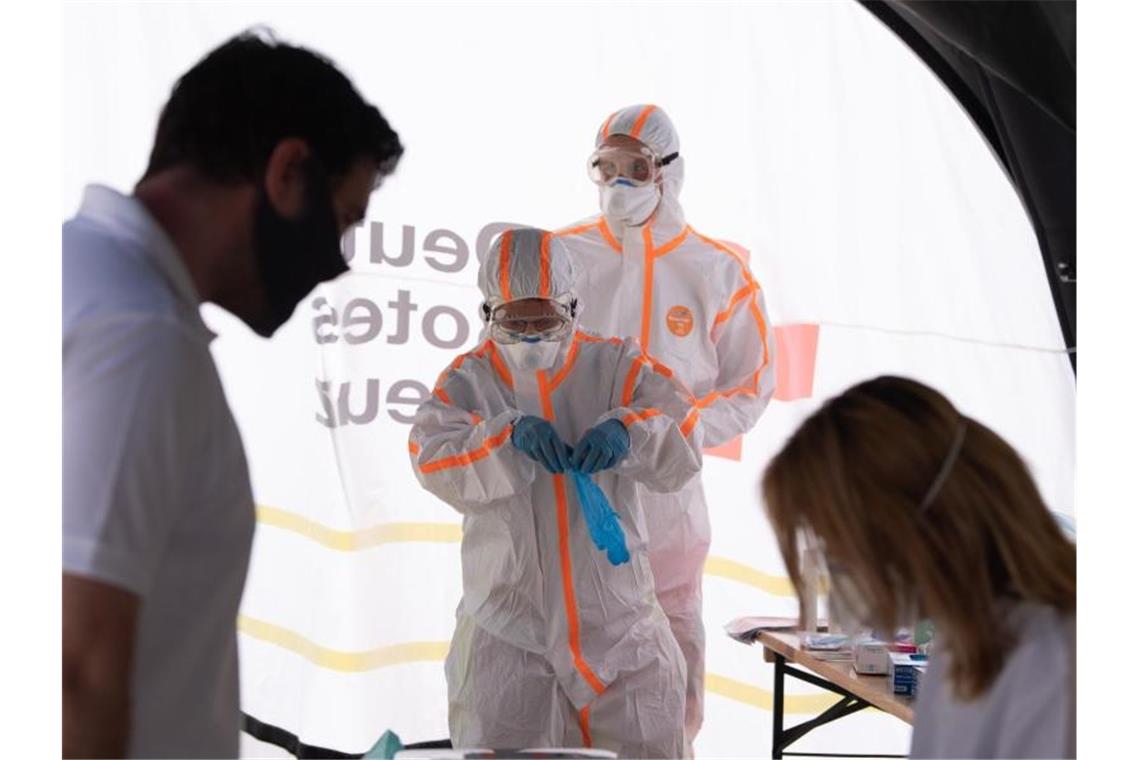 351 registrierte Corona-Neuinfektionen in Deutschland Zwei Mitarbeiter des Deutschen Roten Kreuzes (DRK) in Schutzkleidung in einer mobilen Covid-19-Beprobungsstation. Foto: Sebastian Kahnert/dpa-Zentralbild/dpa