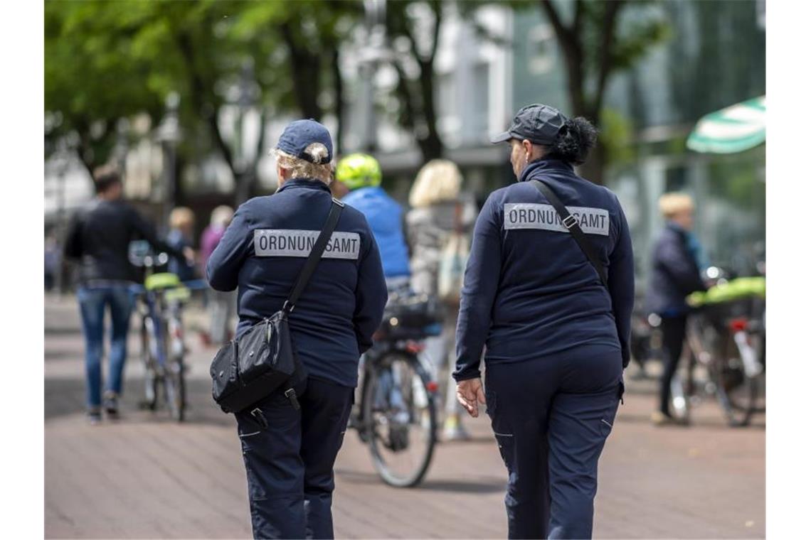 Zwei Mitarbeiterinnen vom Ordnungsamt kontrollieren die Marktstände in der Berliner Straße in der Innenstadt von Gütersloh. Foto: David Inderlied/dpa