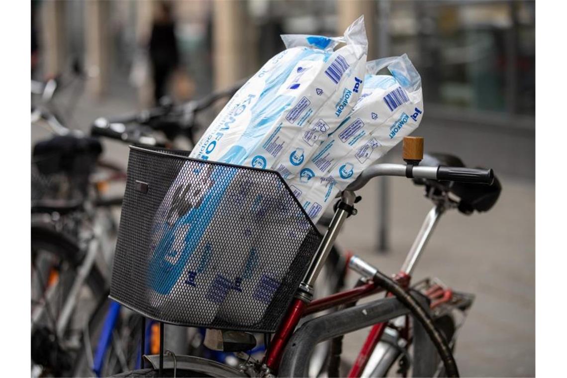 Zwei Packungen Toilettenpapier stecken in einem Fahrradkorb. Foto: Daniel Karmann/dpa/Archivbild